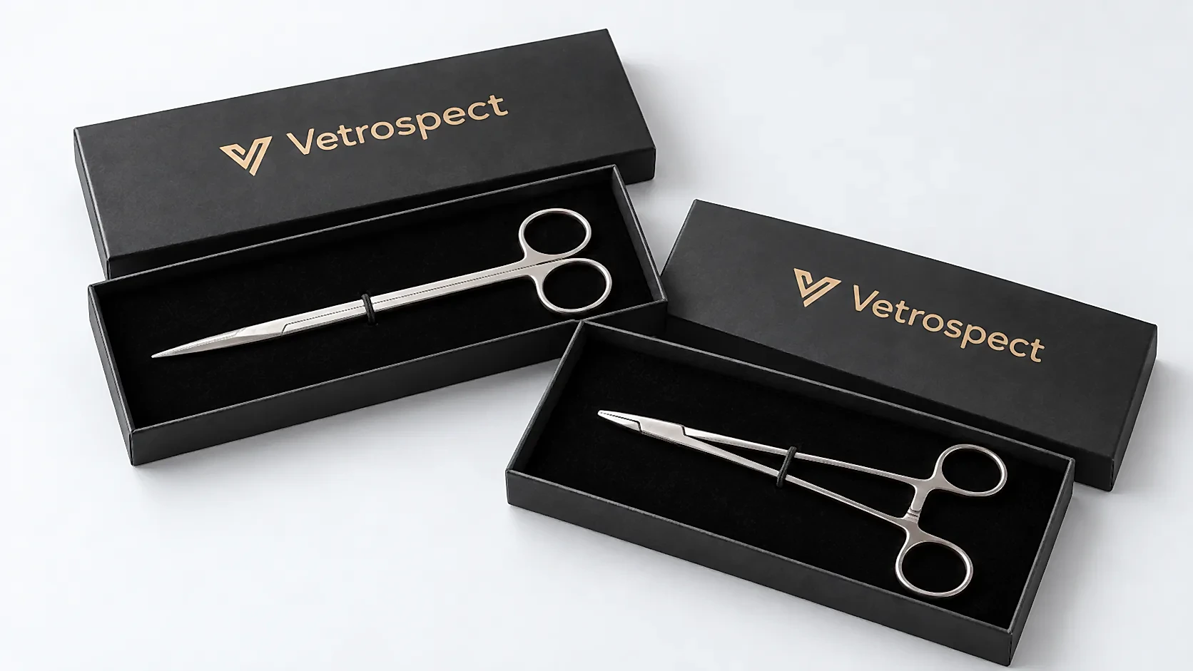 Two open Vetrospect presentation boxes with the gold logo on the lids, holding a pair of scissors and a needle holder